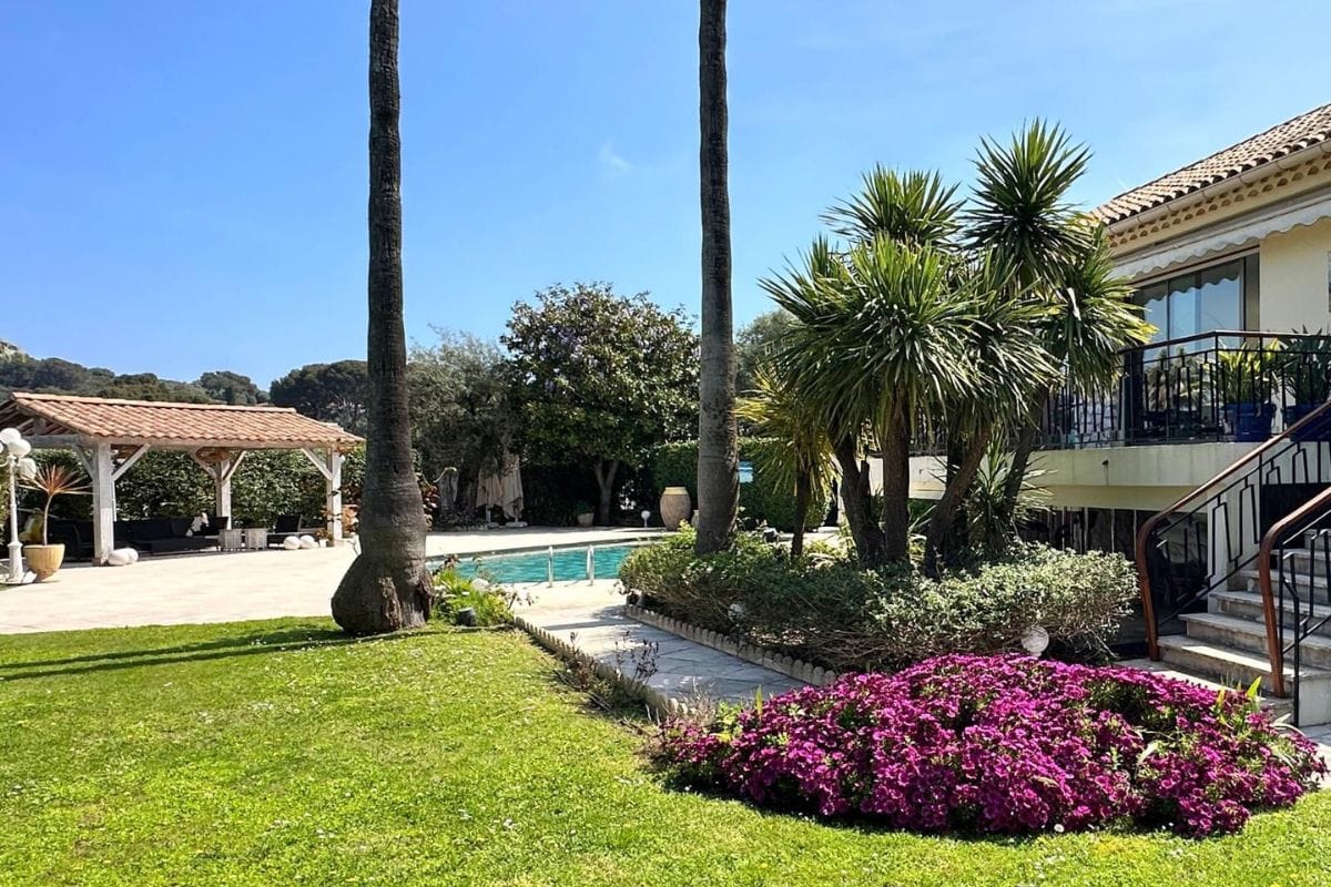 Garden view with palm trees, lawn, and swimming pool at villa cap d’antibes