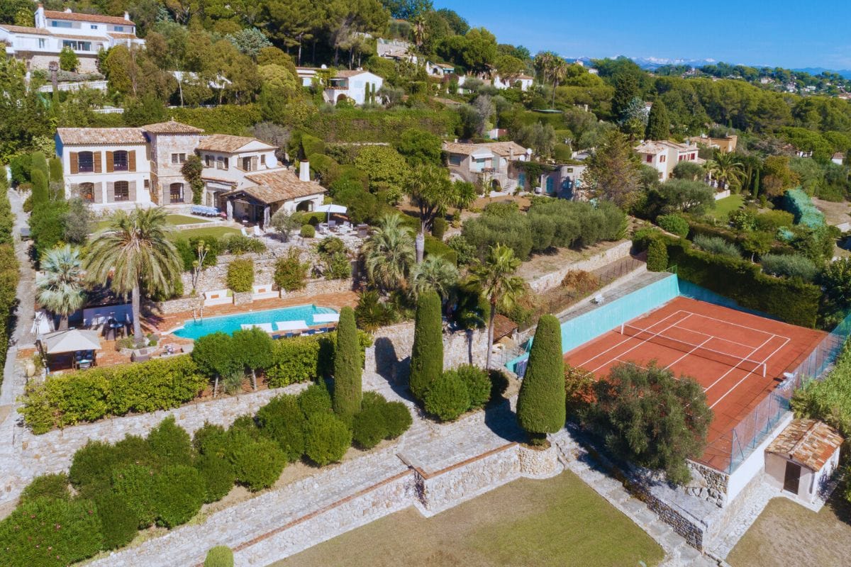 Wide aerial view of the estate showing Villa White House, its' pool area, landscaped gardens and tennis court with Mediterranean scenery.