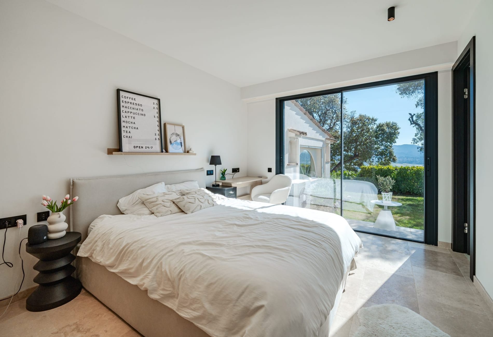 Modern ensuite bedroom with workspace corner and large sliding glass doors in Cannes