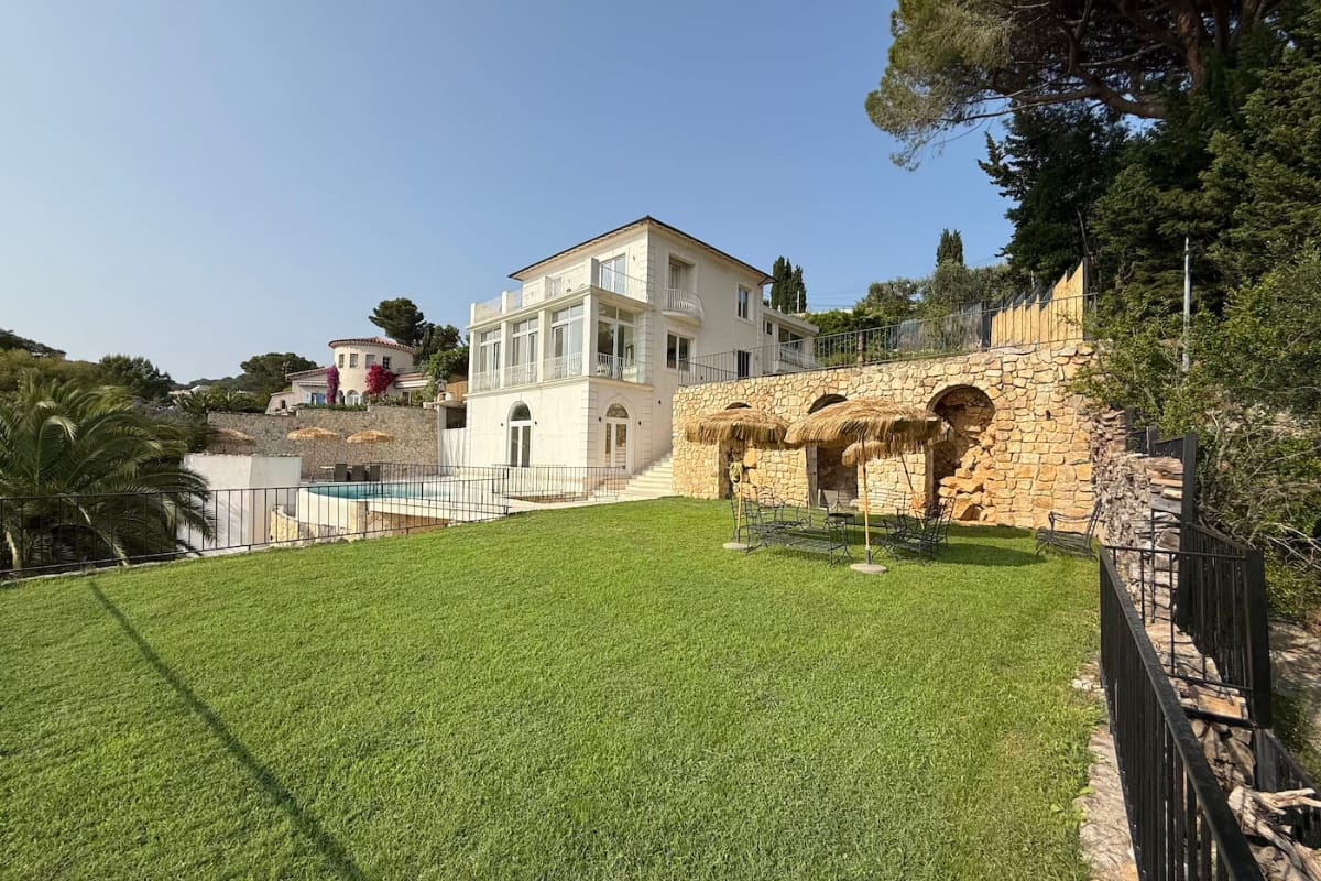 Exterior view of Villa Coralia Cannes with landscaped lawn, stone terraces, and private pool area